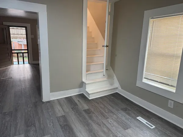 an empty room with wooden floor and windows
