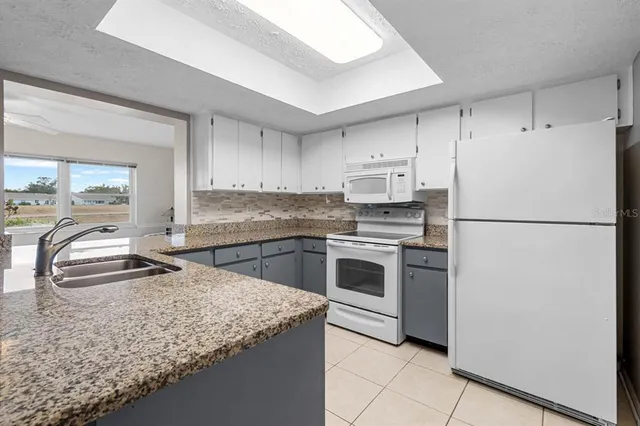 a kitchen with granite countertop a sink appliances and cabinets
