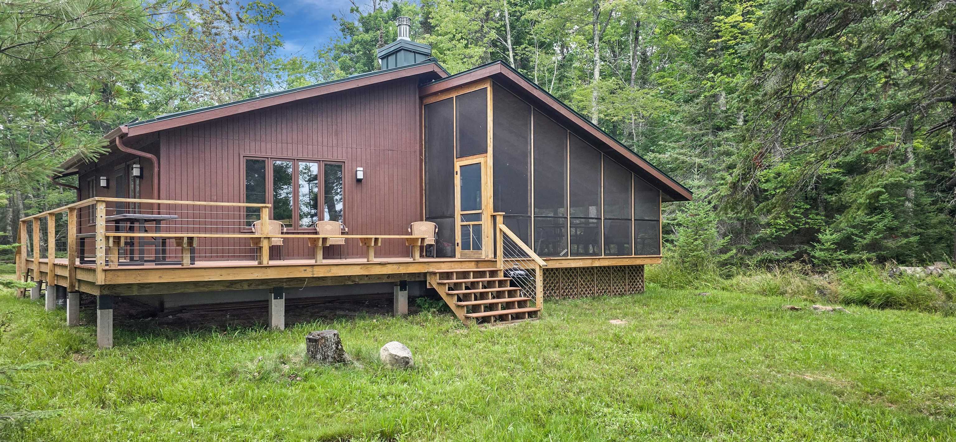 869 South Shore Drive La Pointe, WI 54850 - Photo 1 of 26 Back of house featuring a sunroom, a wooden deck, a lawn, and a view of trees