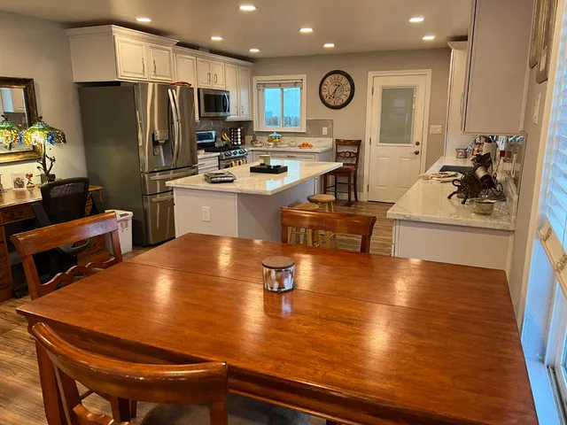 a room with stainless steel appliances dining table and chairs