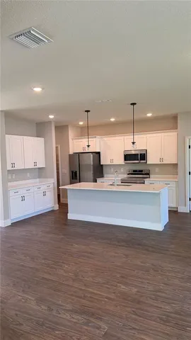 a large kitchen with stainless steel appliances a large counter top a stove and a refrigerator