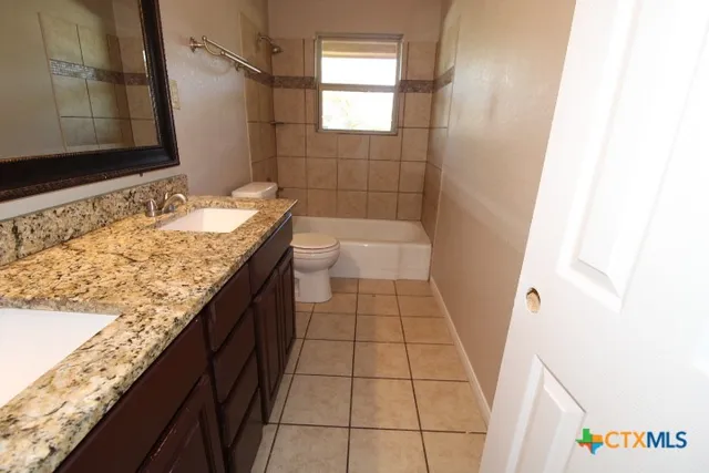 a bathroom with a granite countertop sink a toilet and shower