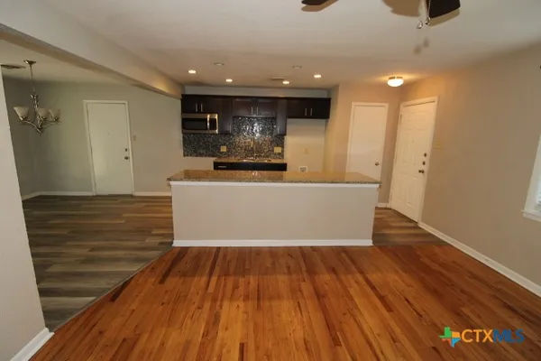 a view of a kitchen with kitchen island a sink wooden floor and a large window