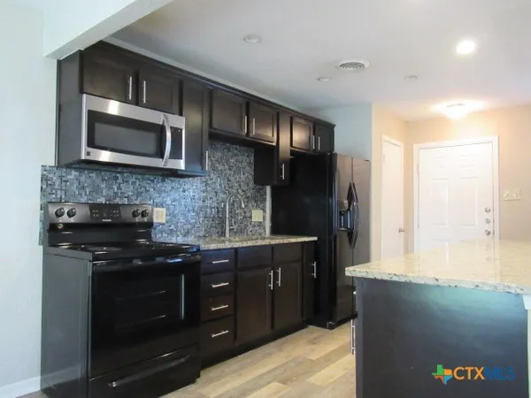 a kitchen with stainless steel appliances granite countertop a stove a microwave and a refrigerator