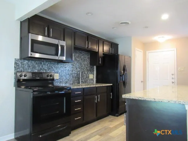 a kitchen with stainless steel appliances granite countertop a stove a microwave and a refrigerator