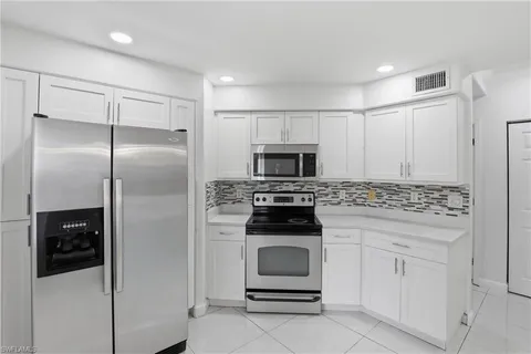 a kitchen with white cabinets and stainless steel appliances