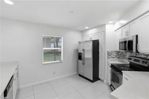 a kitchen with stainless steel appliances a sink a refrigerator a stove and white cabinets with wooden floor