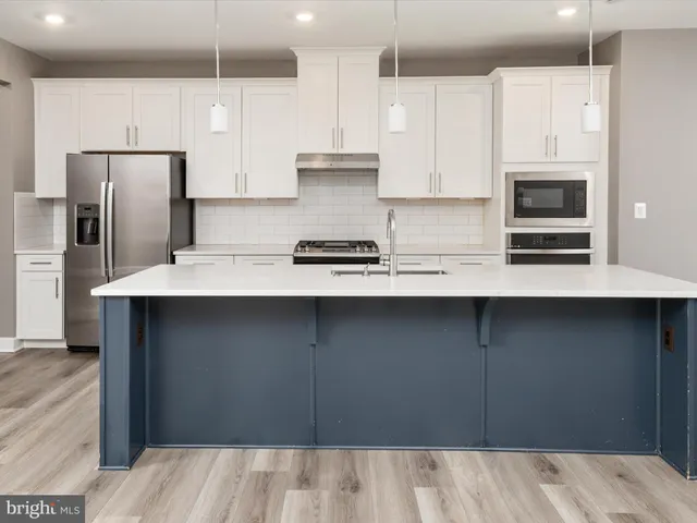 a kitchen with stainless steel appliances kitchen island granite countertop a refrigerator and a stove top oven