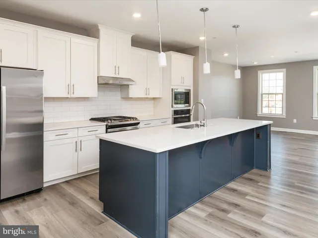 a kitchen with a sink a stove a refrigerator and white cabinets