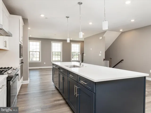 a large kitchen with kitchen island a stove a sink a center island and wooden floor