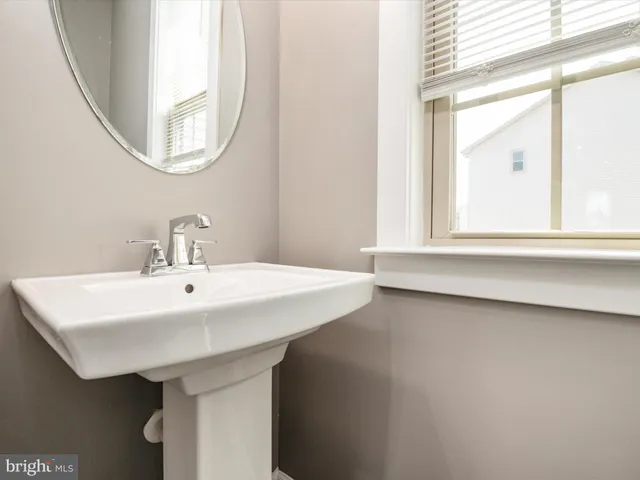 a white sink sitting under a bathroom mirror