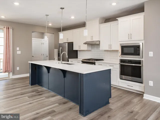 a kitchen with kitchen island white cabinets and stainless steel appliances