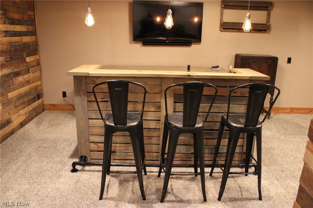 3989 Court Road Wakeman, OH 44889 - Photo 22 of 36 Indoor bar with light colored carpet, light countertops, and decorative light fixtures