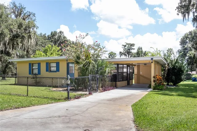 a view of house with a yard and large tree