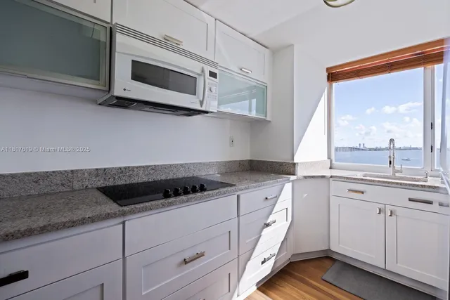 a kitchen with granite countertop white cabinets and black appliances