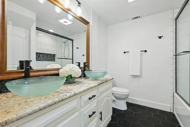 a bathroom with a granite countertop sink a toilet a mirror and shower