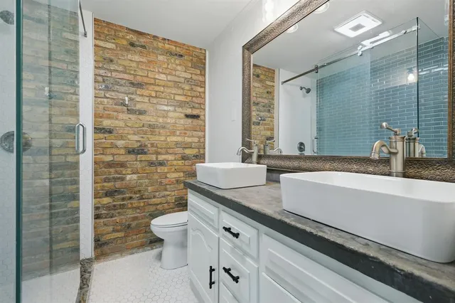 a bathroom with a granite countertop sink a toilet a mirror and shower