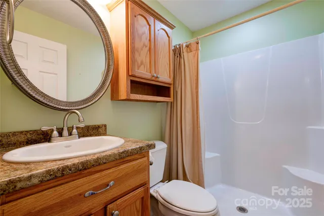 a bathroom with a granite countertop sink mirror vanity and toilet