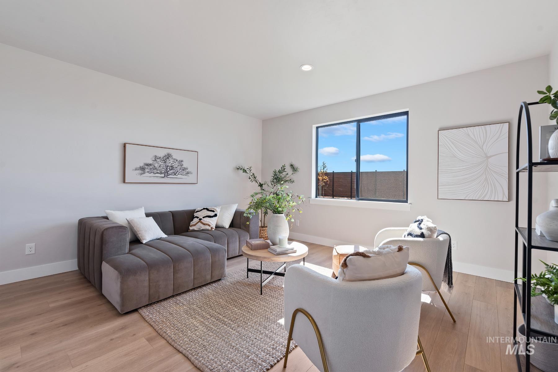 8410 West Graye Street, Unit ALPINE Meridian, ID 83646 - Photo 11 of 45 Expansive living area with wood-finish flooring, a vertical panel accent wall, and a contemporary chandelier