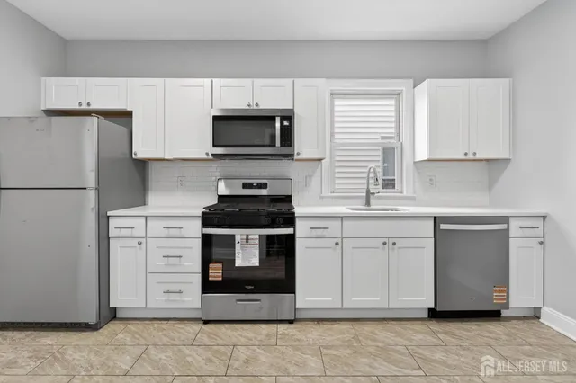 a kitchen with white cabinets stainless steel appliances and a window