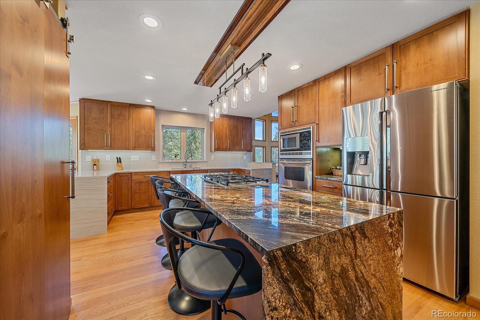 9948 South Turkey Creek Road Conifer, CO 80433 - Photo 13 of 50 a kitchen with stainless steel appliances granite countertop a refrigerator a stove a sink a dining table and chairs with wooden floor