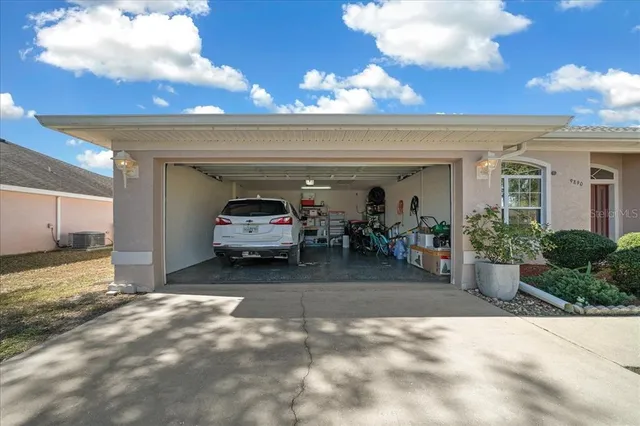 a view of a white house with a yard plants and large tree