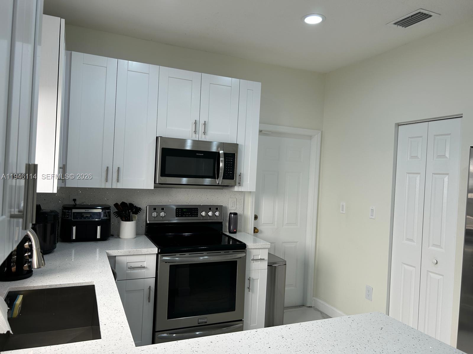22844 Southwest 114th Avenue Miami, FL 33170 - Photo 38 of 40 a kitchen with stainless steel appliances a stove a microwave a sink and cabinets