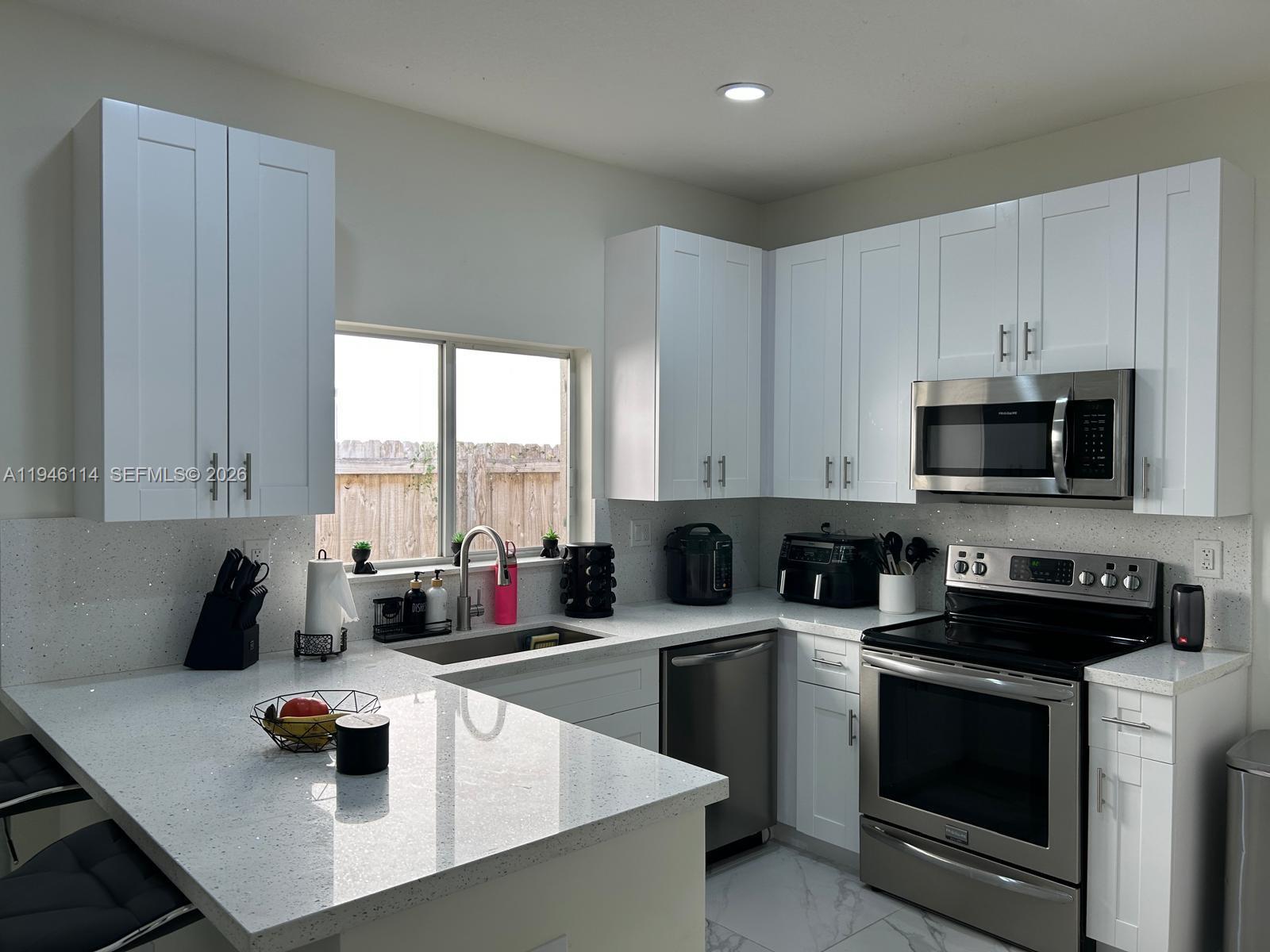 22844 Southwest 114th Avenue Miami, FL 33170 - Photo 39 of 40 a kitchen with a sink a stove and cabinets