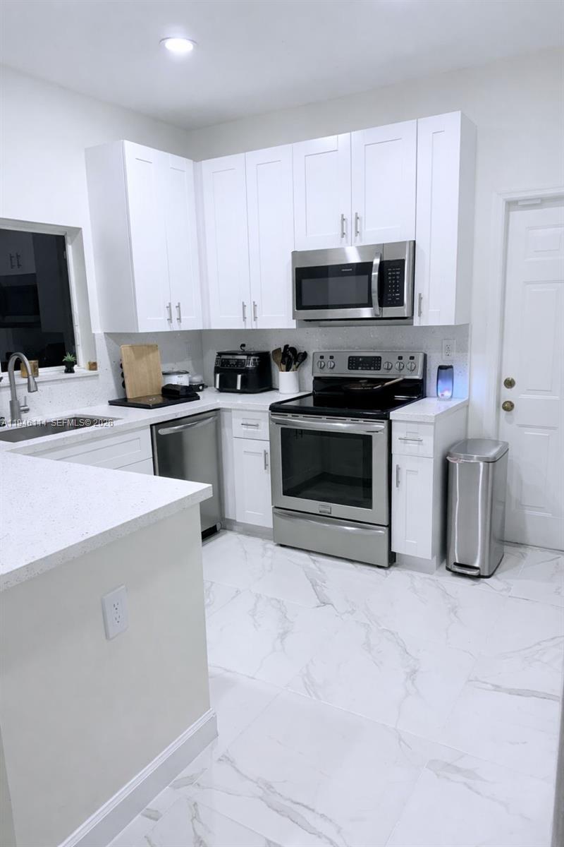 22844 Southwest 114th Avenue Miami, FL 33170 - Photo 5 of 40 a kitchen with stainless steel appliances and white cabinets