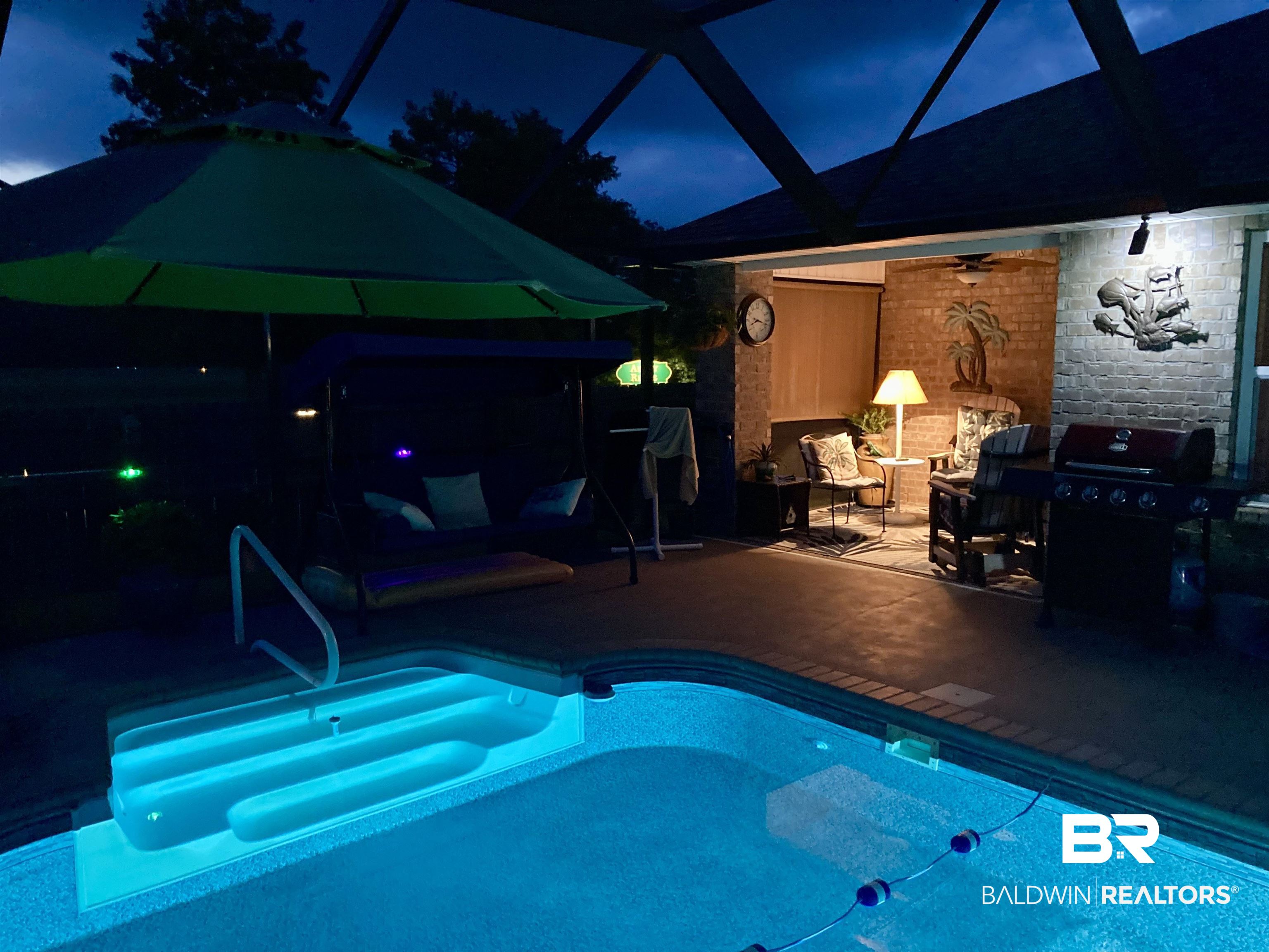 1676 Abbey Loop Foley, AL 36535 - Photo 28 of 31 Screened outdoor living area featuring a built-in swimming pool with illuminated steps, a brick-faced wall, and integrated overhead lighting