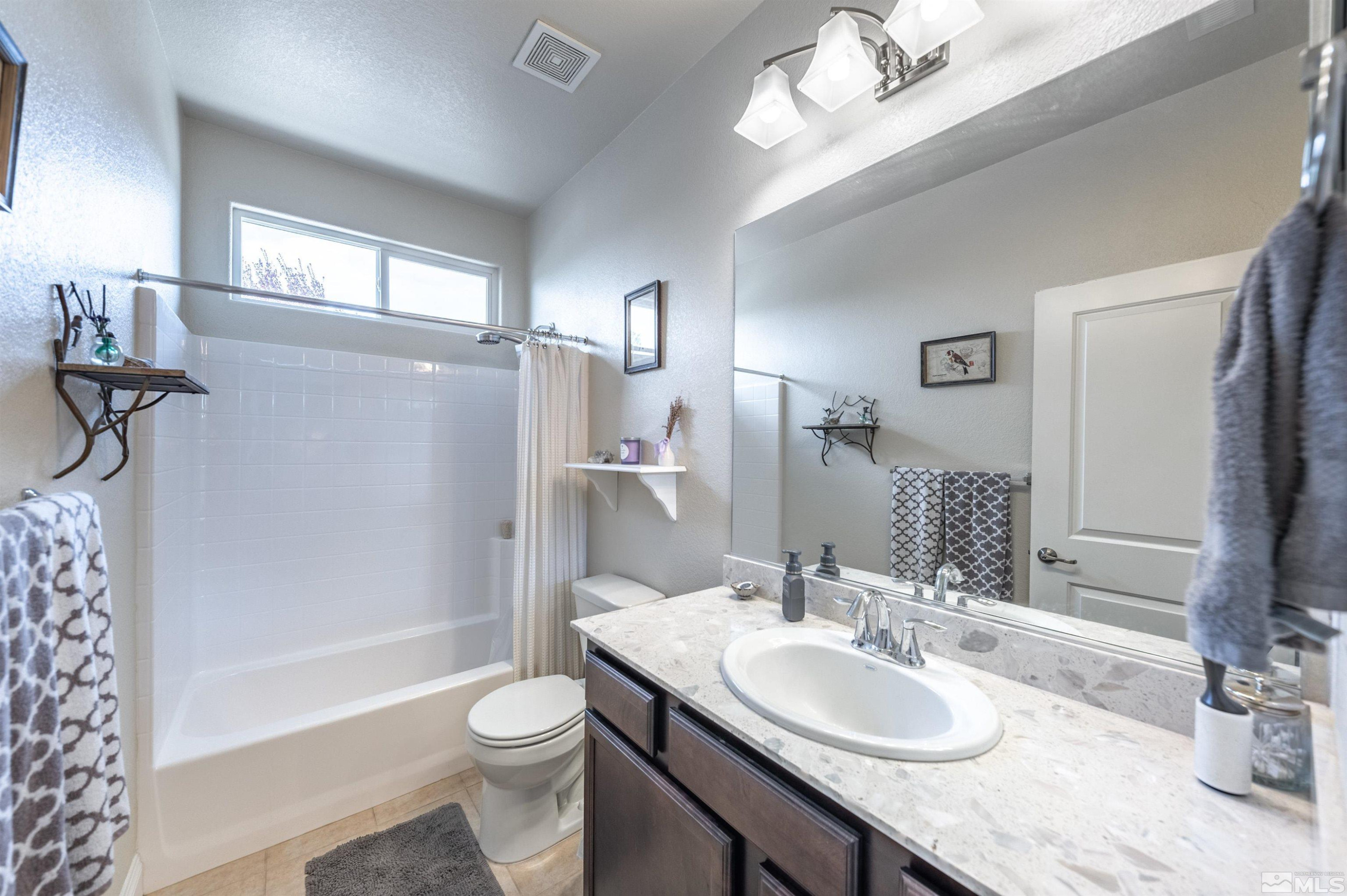 7080 Truth Drive Sparks, NV 89436 - Photo 24 of 40 a bathroom with a granite countertop sink toilet a mirror and shower