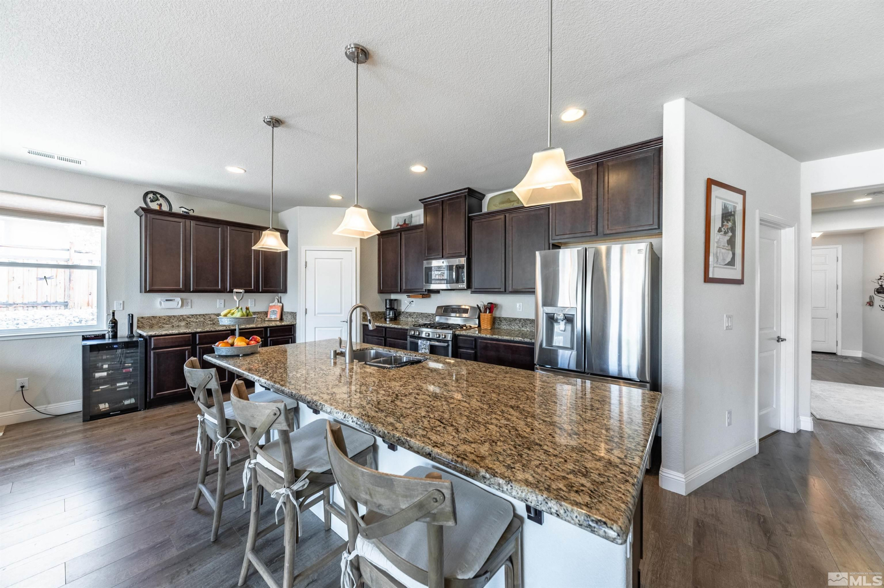 7080 Truth Drive Sparks, NV 89436 - Photo 8 of 40 a kitchen with refrigerator a stove a dining table and chairs with wooden floor
