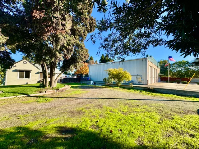 a view of a house with a yard and large trees