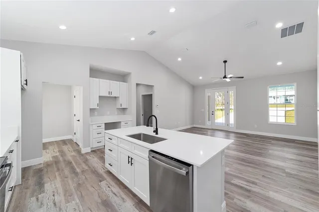 a view of a kitchen with center island wooden floor appliances and windows