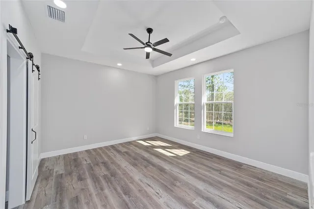 a view of an empty room with a window and wooden floor