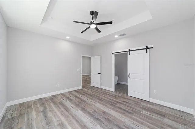 a view of empty room with wooden floor and ceiling fan