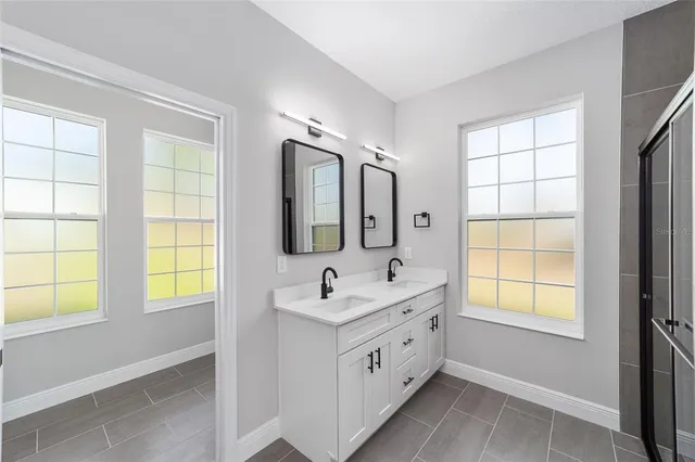a bathroom with a sink mirror and a bathtub next to a window