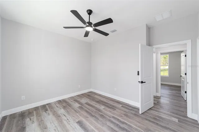 an empty room with wooden floor and a ceiling fan