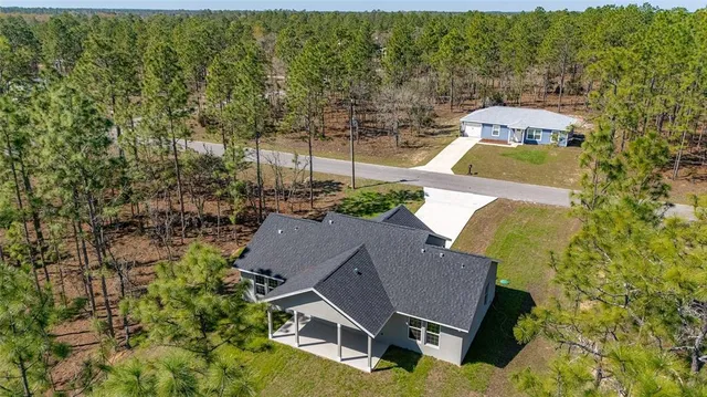 an aerial view of residential houses with outdoor space and trees