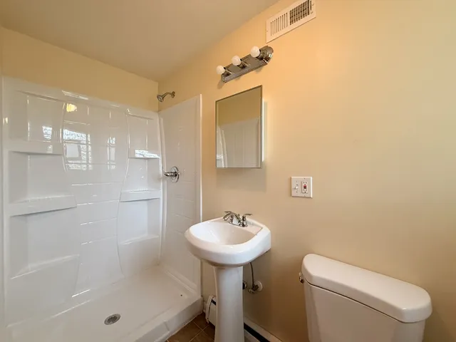 a bathroom with a sink a toilet and shower