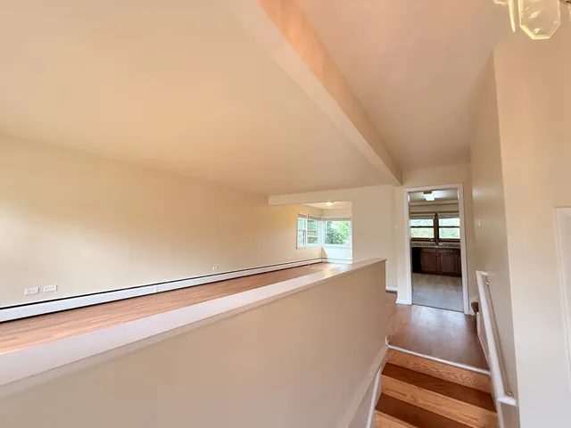 a view of a hallway with wooden floor and kitchen