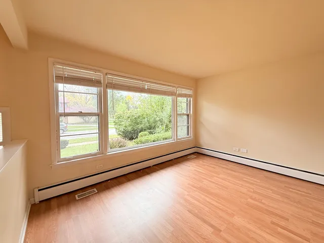 a view of an empty room with a window and wooden floor