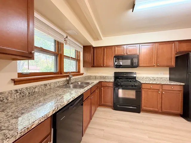 a kitchen with stainless steel appliances granite countertop a stove a sink and a microwave