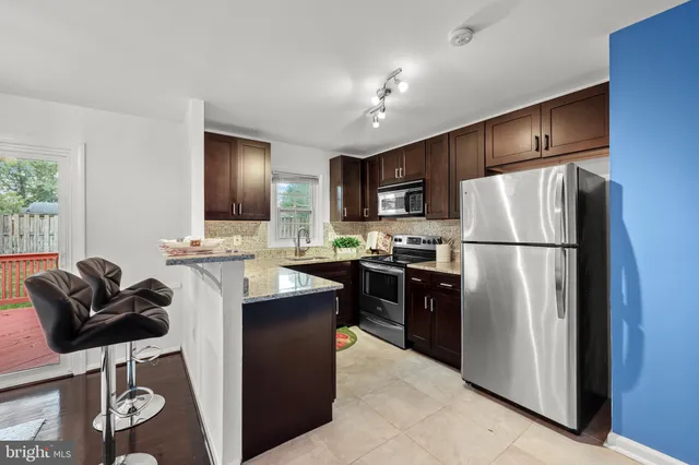 a kitchen with stainless steel appliances granite countertop a refrigerator a stove a sink a dining table and chairs