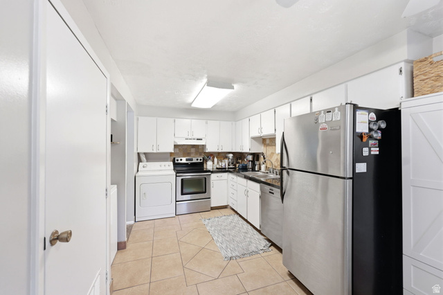 314 West Center Street, Unit F102 Bountiful, UT 84010 - Photo 15 of 29 Kitchen featuring white cabinetry, tile flooring, stainless steel appliances, a tile backsplash, and an integrated laundry area with a washer and dryer