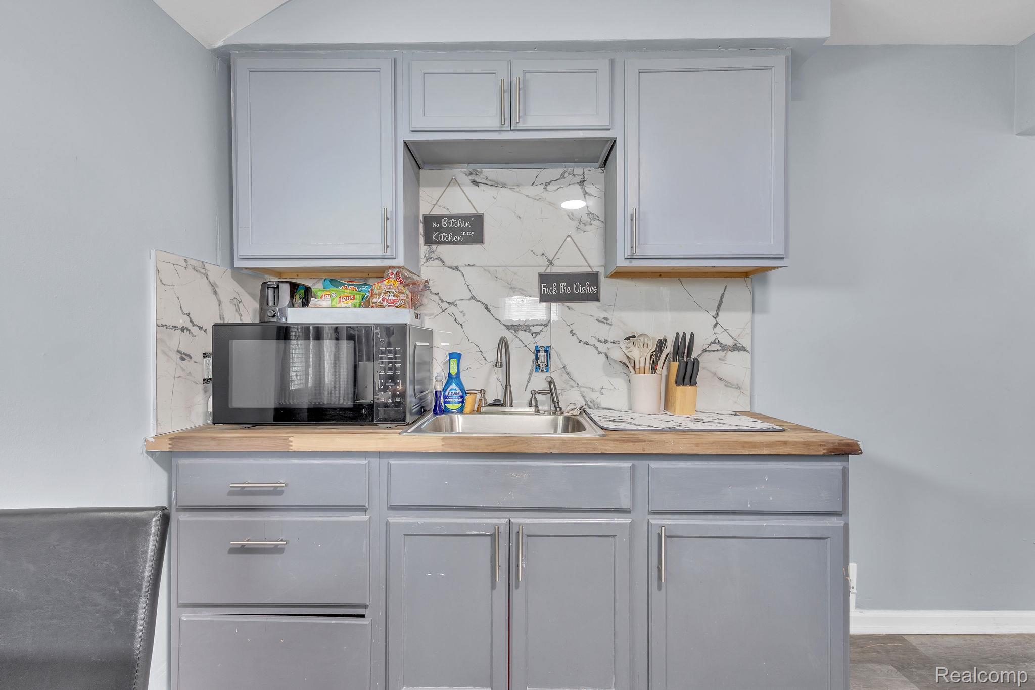 8401 Fielding Street Detroit, MI 48228 - Photo 11 of 34 Kitchen featuring gray cabinetry, wooden counters, black microwave, and tasteful backsplash