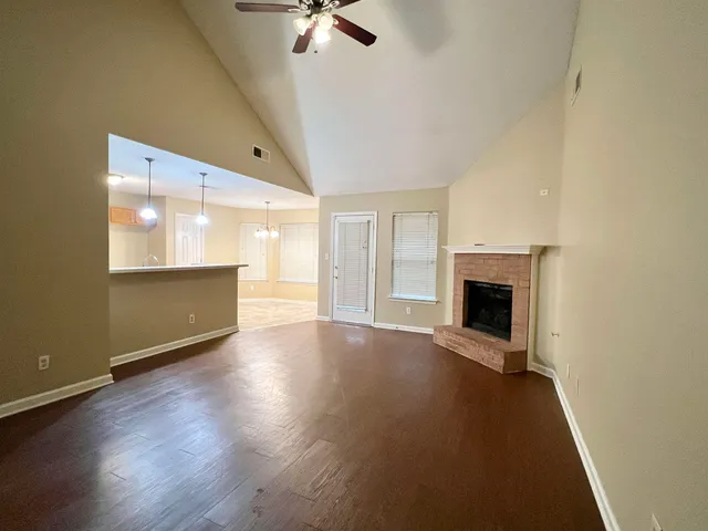 an empty room with wooden floor fireplace and windows