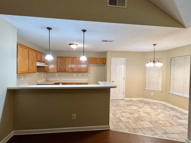 a view of a kitchen with kitchen island a sink wooden floor and a counter top space