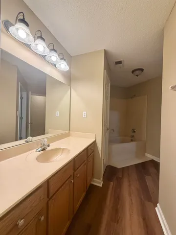 a bathroom with a double vanity sink and mirror with bathtub