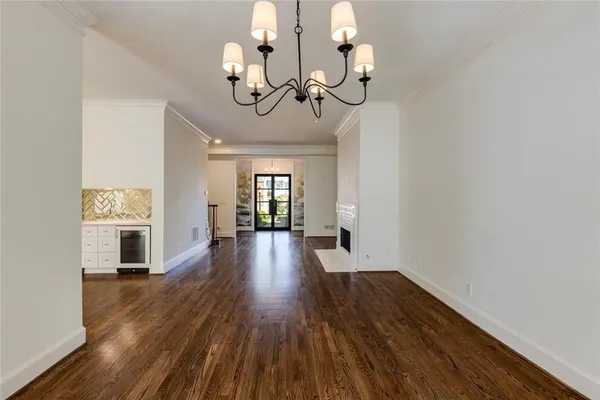 a view of a room with wooden floor chandelier and windows